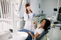 Healthy teeth and caries prevention concept. Young pretty African woman at the dentist`s chair during a dental Royalty Free Stock Photo