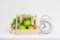 Healthy time and dieting concept. Vintage retro alarm clock and green apples and lettuce in wood basket on grunge white wooden