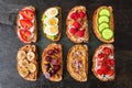 Healthy toast set with assorted protein spreads, fruits, nuts and vegetables over a dark background