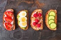 Healthy toast set with a variety of proteins and fruits. Top view on a dark background.