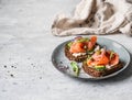 Healthy toasts with rye bread with cream cheese, salmon, fresh cucumber, capers, sesame seeds, black pepper and arugula on plate Royalty Free Stock Photo