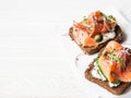 Healthy toasts with rye bread with cream cheese, salmon, fresh cucumber, capers, sesame seeds, black pepper and arugula on white Royalty Free Stock Photo