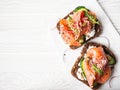 Healthy toasts with rye bread with cream cheese, salmon, fresh cucumber, capers, sesame seeds, black pepper and arugula on white Royalty Free Stock Photo