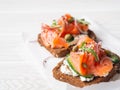 Healthy toasts with rye bread with cream cheese, salmon, fresh cucumber, capers, sesame seeds, black pepper and arugula on white Royalty Free Stock Photo