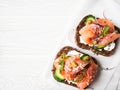 Healthy toasts with rye bread with cream cheese, salmon, fresh cucumber, capers, sesame seeds, black pepper and arugula on white Royalty Free Stock Photo