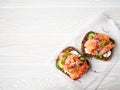 Healthy toasts with rye bread with cream cheese, salmon, fresh cucumber, capers, sesame seeds, black pepper and arugula on white Royalty Free Stock Photo