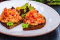 Healthy toasts with rye bread with salmon, avocado mousse, lettuce on white plate