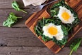 Healthy toasts with spinach and egg on a wood board, top view table scene over wood