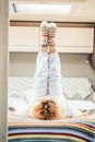 Healthy traveler woman doing stretching and workout exercises inside a campe van bedroom getting up the legs. Alternative van life