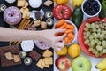 Healthy and unhealthy food concept, fruits and vegetables vs donuts, sweets and chocolate with woman`s hand. Top view Royalty Free Stock Photo