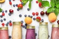 Healthy and useful colorful berry cokctalis, smoothies and milkshakes with yogurt, fresh fruit and berries on gray table, top view