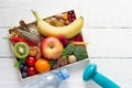 Healthy food on tray and dumbbells on white wooden background, balanced diet concept and healthy lifestyle