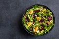 Healthy vegan avocado, orange and beet salad in black bowl, dark background