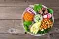 Healthy vegan buddha bowl with avocado, sweet potato, kale and vegetables, above view over rustic wood