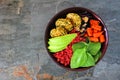 Healthy vegan buddha bowl with falafels, beet quinoa, avocado, and vegetables, top view on a dark stone background