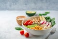 Healthy vegan buddha bowl with spinach, tomato, chickpea, quinoa, radish, beans, avocado, mini corn and tofu cheese