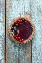 Healthy vegan dessert. Homemade tart with nut crust and berry jelly filling decorated with organic currants on shabby blue Royalty Free Stock Photo