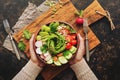 Healthy vegan diet salad with fresh vegetables-avocado, radish, tomato, cucumber, celery, nuts and seeds.Girl in wool sweater