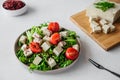 Healthy vegan diet salad of tofu, herbs and tomatoes on white table. two-pronged fork, block of cheese on cutting bamboo board,