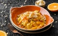 Healthy vegan dish, cooked rice with raisins, cauliflower, orange and almonds in ceramic plate over dark background. Healthy food