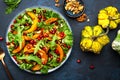 Healthy vegan eating, autumn pumpkin salad with baked honey pumpkin slices, lettuce, arugula, pomegranate seeds and walnuts. Royalty Free Stock Photo