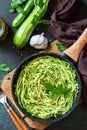 Healthy vegan food, low carb dish. Cooked zucchini noodles with basil and garlic in a cast iron pan