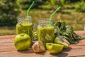 Healthy Vegan Green Smoothie With Spinach, apple, celery, kiwi, Brussels sprout, avocado, in glass jars, outdoor, over nature