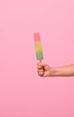 Healthy vegan ice cream popsicle in hand of a baby girl with pink wall at background with copy space . Summer dessert and cheerful