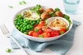 Healthy vegan lunch bowl with falafel hummus tomato avocado peas