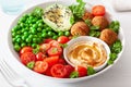 Healthy vegan lunch bowl with falafel hummus tomato avocado peas