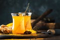 Healthy vegan turmeric golden tea with honey in glass cup on wooden tray. Herbal healing spicy tea