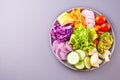 Healthy vegetable buddha bowl lunch with quinoa, red cabbage, tomatoes, onion, green salad, cucumber on gray background. Top view Royalty Free Stock Photo