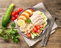 Healthy vegetable buddha bowl lunch with turkey, vegetables and quinoa on brown wooden background. Top view.