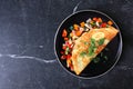 Healthy vegetable omelette plate over a dark stone background