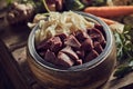 Healthy vegetables scattered on table near dog bowl with chicken liver and cartilages Royalty Free Stock Photo