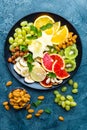 Healthy vegetarian bowl dish with fresh fruits and nuts. Plate with raw apple, orange, grapefruit, banana, kiwi, lemon, grape, alm Royalty Free Stock Photo