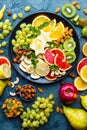 Healthy vegetarian bowl dish with fresh fruits and nuts. Plate with raw apple, orange, grapefruit, banana, kiwi, lemon, grape, alm Royalty Free Stock Photo