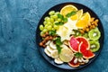 Healthy vegetarian bowl dish with fresh fruits and nuts. Plate with raw apple, orange, grapefruit, banana, kiwi, lemon, grape, alm Royalty Free Stock Photo