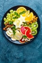 Healthy vegetarian bowl dish with fresh fruits and nuts. Plate with raw apple, orange, grapefruit, banana, kiwi, lemon, grape, alm Royalty Free Stock Photo