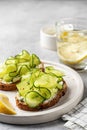 Healthy vegetarian breakfast with cucumber sandwiches with soft cheese and lemon water on gray background