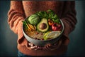 Healthy vegetarian dinner. Woman in jeans and warm sweater holding bowl with fresh salad, avocado, grains, beans, roasted