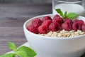 Healthy vegetarian food. Oatmeal with raspberry and mint leaves. Brown wooden background