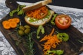 Healthy vegetarian sandwich with carrot, Tomato, lettuce and spices, served on an wooden board