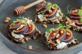 Healthy vegetarian toasts with figs, cheese, nuts and honey on rustic tray close-up