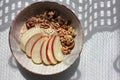 Healthy Walnut Red Apple Oatmeal in vintage bowl on white wooden table background. Natural lighting. Beautiful openwork shadow fro