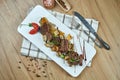 Healthy warm salad with grilled beef and vegetables on a white ceramic plate. Composition with salad and spices on a wooden