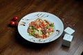 Healthy warm salad with grilled beef and vegetables on a white ceramic plate. Composition with salad and spices on a wooden