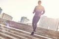 Healthy way of life. Full length portrait of athletic african man in sportswear running down stairs on a sunny warm day