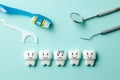 Healthy white teeth are smiling and tooth with caries is sad on green mint background. Toothbrush and dentist tools mirror, hook. Royalty Free Stock Photo