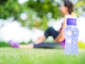 Healthy woman athlete is resting on grass. Focus on bottle of water. Royalty Free Stock Photo